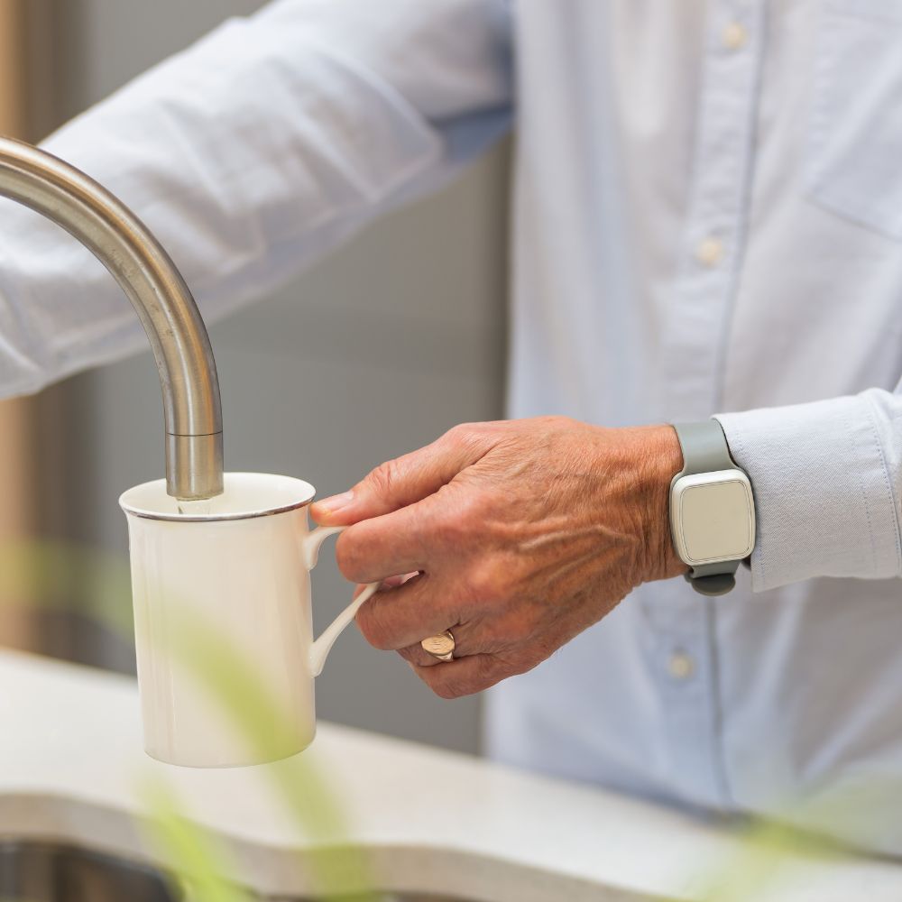 Older male filling a white mug with water from the tap 