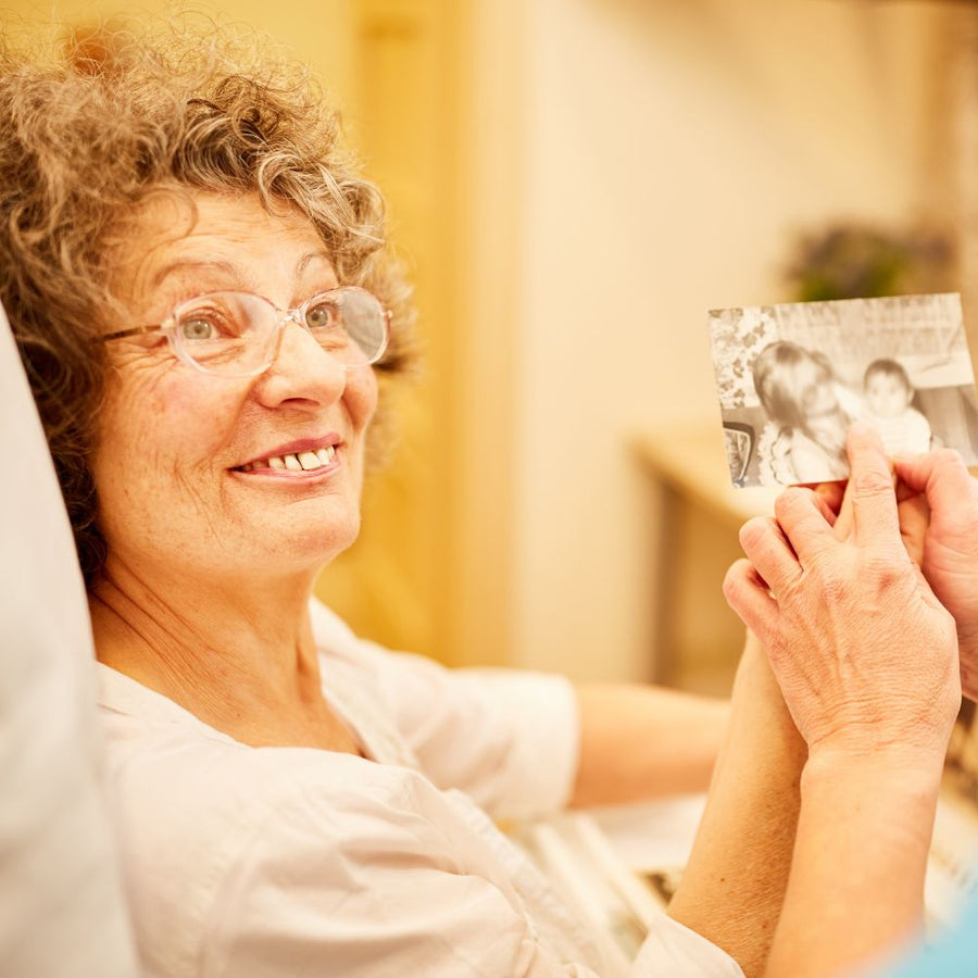 Woman holding a photograph of a couple, smiling warmly.