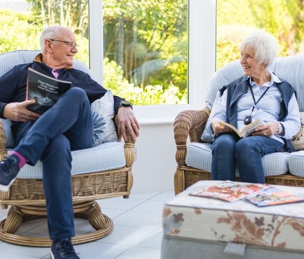 Elderly couple relaxing at home, with the woman wearing a HelpAlert personal alarm pendant for safety and peace of mind.