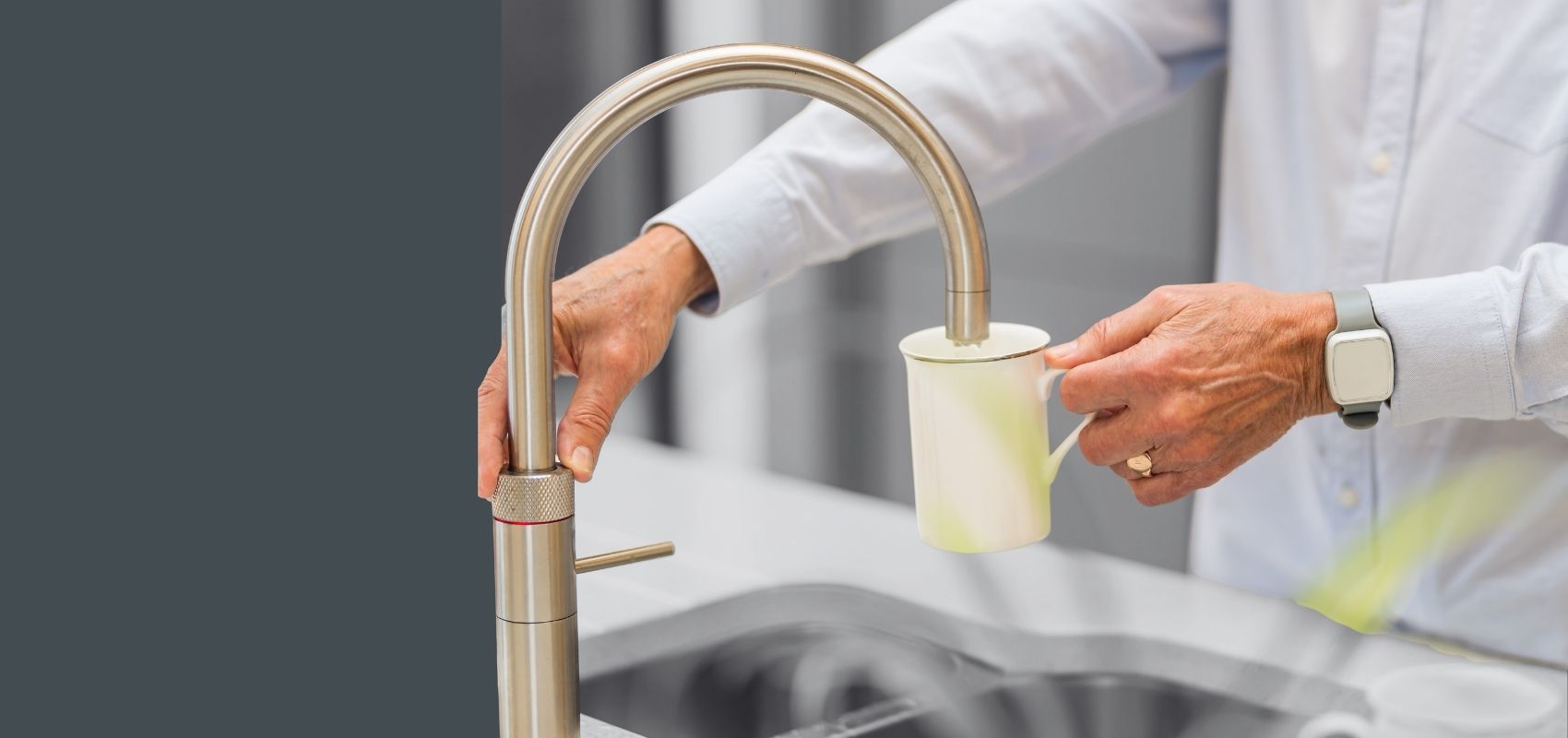 Older adult wearing a HelpAlert watch alarm while making tea in the kitchen, showing everyday use.